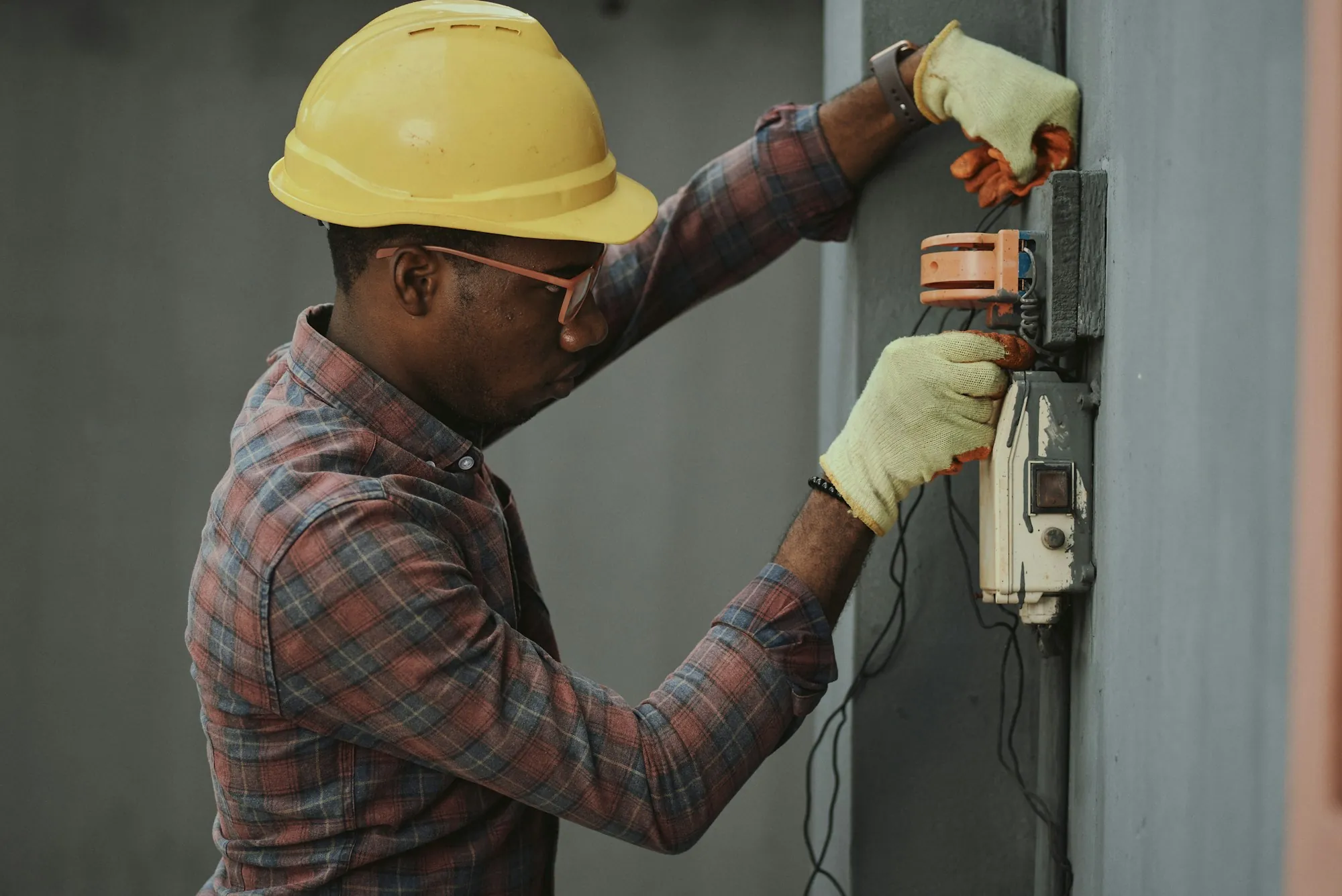 Electrician in a hard hat checking a residential electrical panel