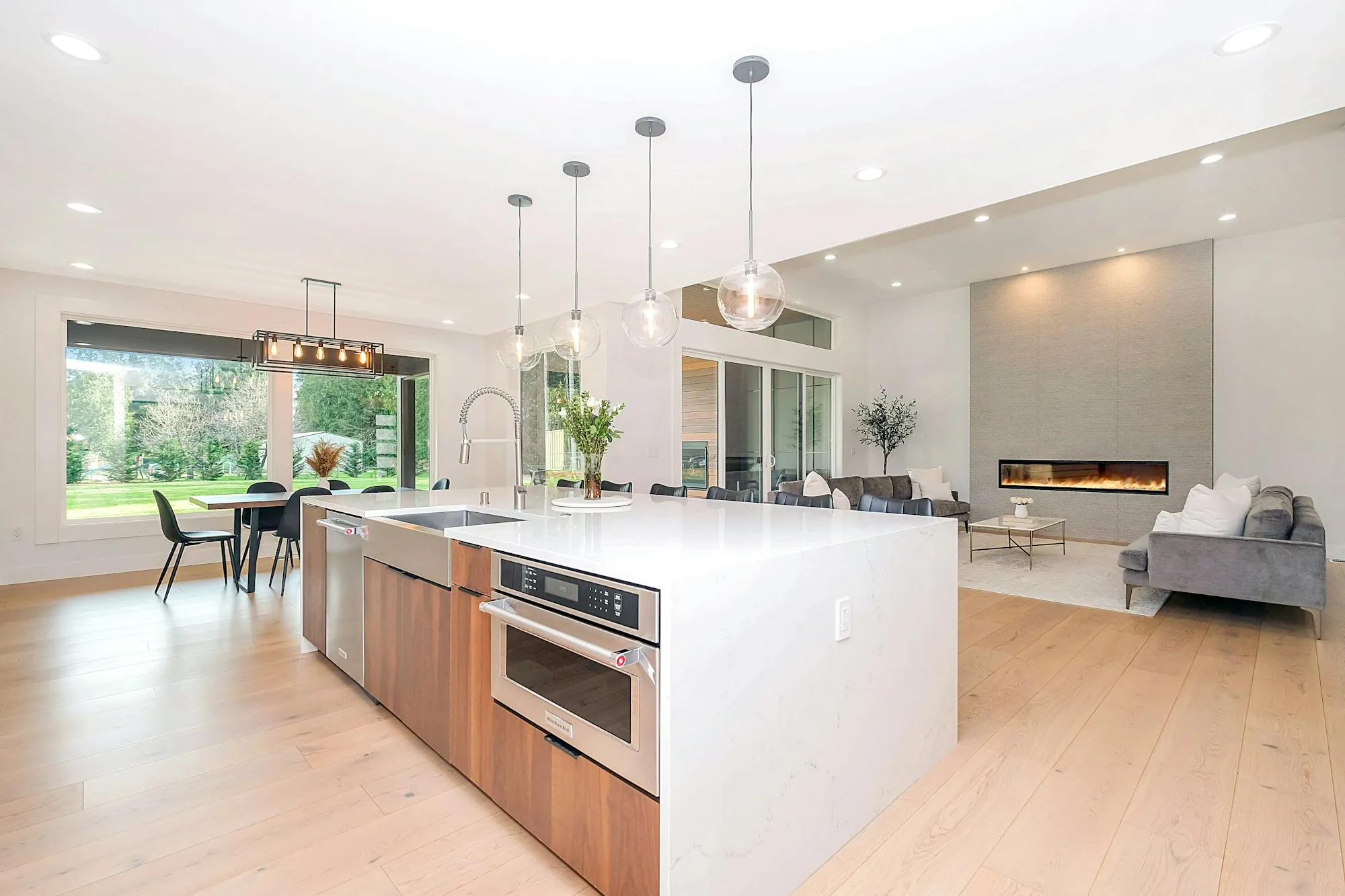 Bright kitchen with pendant lights over a long island and recessed lighting along the ceiling